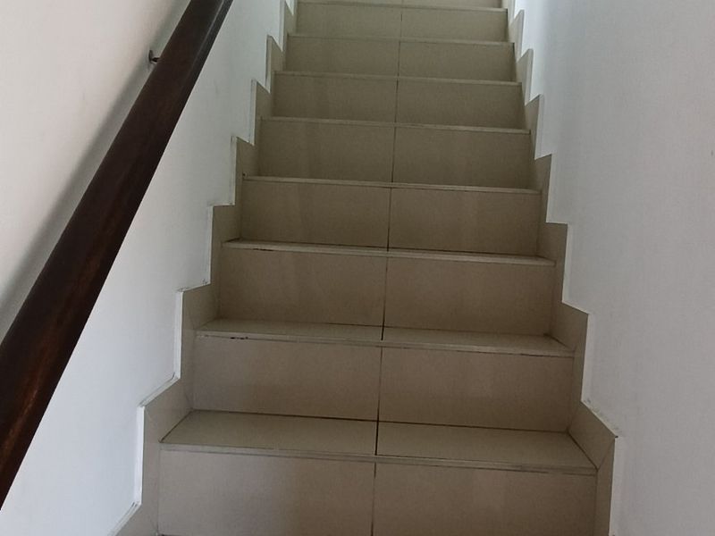 A functional interior staircase featuring tiled steps and a wooden handrail, leading to an upper level.