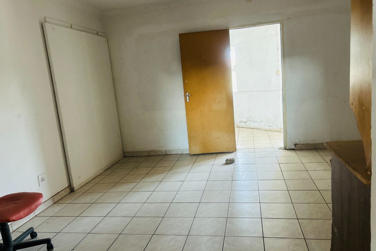 An empty bedroom featuring tiled flooring and a built-in cupboard, requiring cosmetic updates to the walls and finishes.