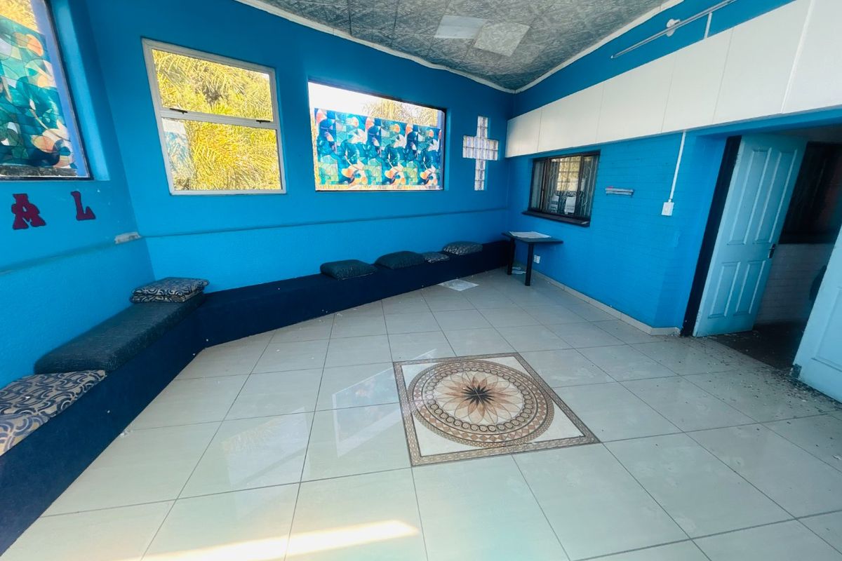 An open-plan commercial space featuring tiled flooring with a decorative inlay, built-in bench seating, and unique glass block window accents.
