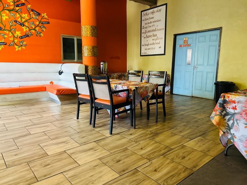 Open plan commercial dining area featuring wood-look tiled flooring, built-in bench seating, and a decorative column in a vibrant, casual setting.