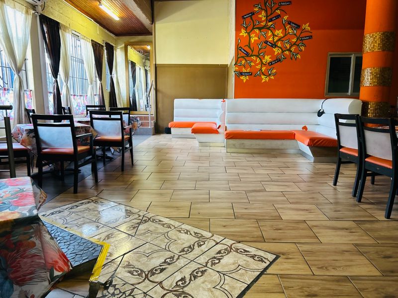 Open plan commercial dining area featuring built-in bench seating, wood-look tiled flooring, and a decorative feature wall.