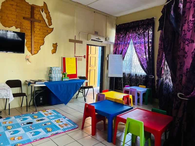 A multi-purpose commercial space featuring tiled flooring, a split-system air conditioner, and an exposed brick feature wall, currently utilized as a children's activity area.