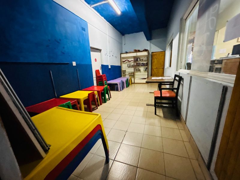 A functional commercial space featuring ceramic tile flooring, built-in shelving, and overhead lighting, suitable for a classroom or office environment.