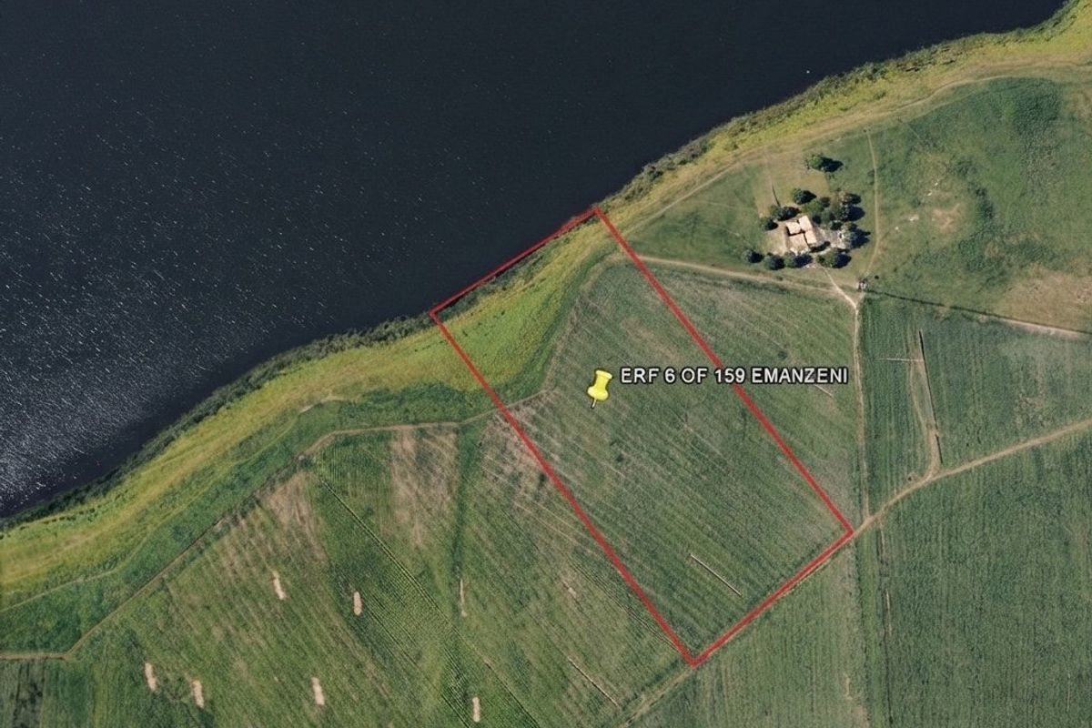Aerial view of a vacant residential plot situated directly along the waterfront, offering potential for development.