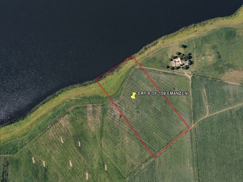 Aerial view of a vacant residential plot situated directly along the waterfront, offering potential for development.