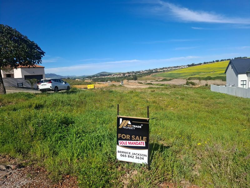 A vacant residential plot of land featuring open grass, boundary fencing, and surrounding neighborhood views, ideal for new construction.