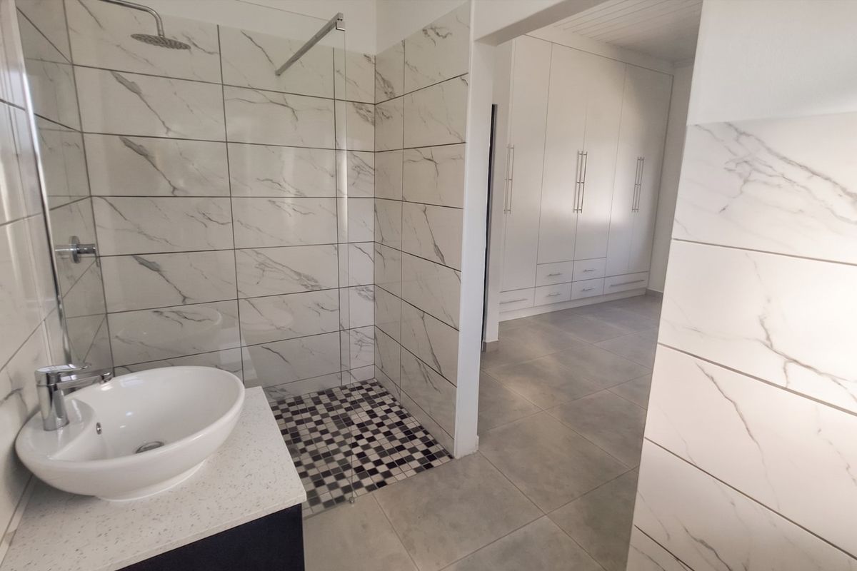 Modern bathroom featuring a walk-in shower with marble-look tiling, a vessel sink on a vanity, and adjacent built-in storage cabinetry.