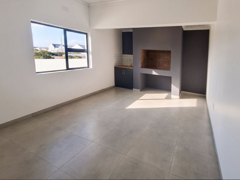 Spacious living area featuring large windows, neutral tiled flooring, and a built-in fireplace with adjacent cabinetry.
