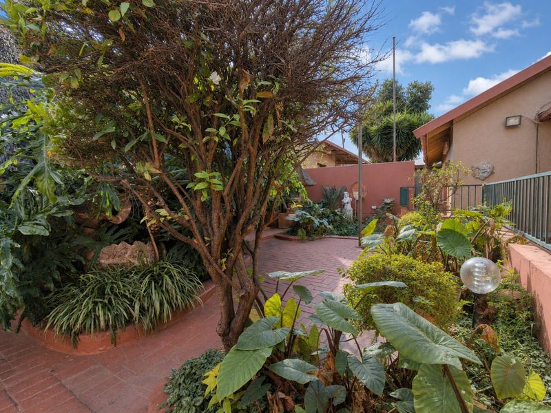A landscaped garden area featuring brick paving, established trees, and retaining walls, providing a private outdoor space adjacent to the house.
