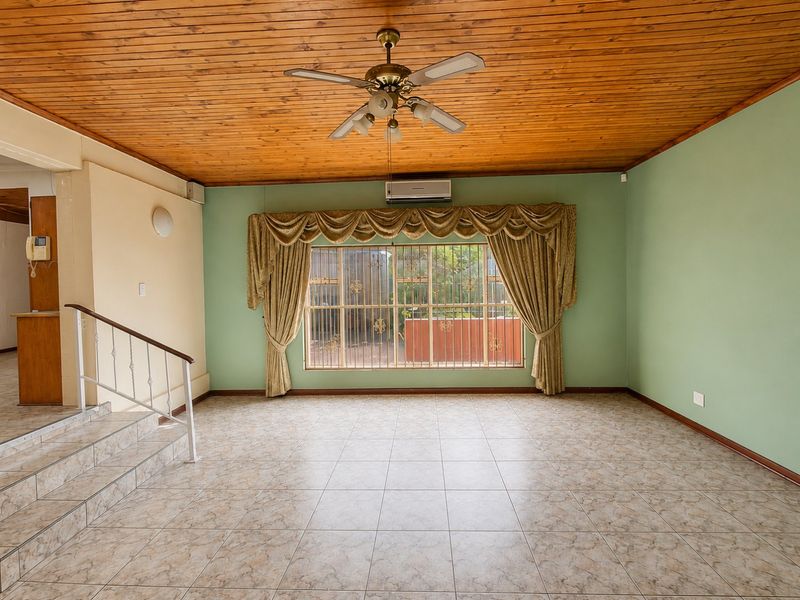 Spacious living area featuring timber ceiling, tiled flooring, split system air conditioning, and a staircase with wrought iron railing.