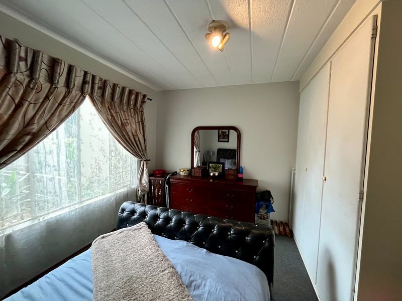 A functional bedroom featuring built-in cupboards, a large window for natural light, and a standard ceiling light fixture.