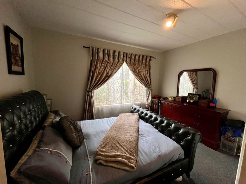 A standard bedroom featuring carpeted flooring and a tiled ceiling, providing a functional and comfortable sleeping space.