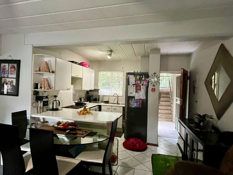 Open plan kitchen and dining area featuring tiled flooring, built-in cabinetry, and a breakfast counter, with direct access to an external staircase.