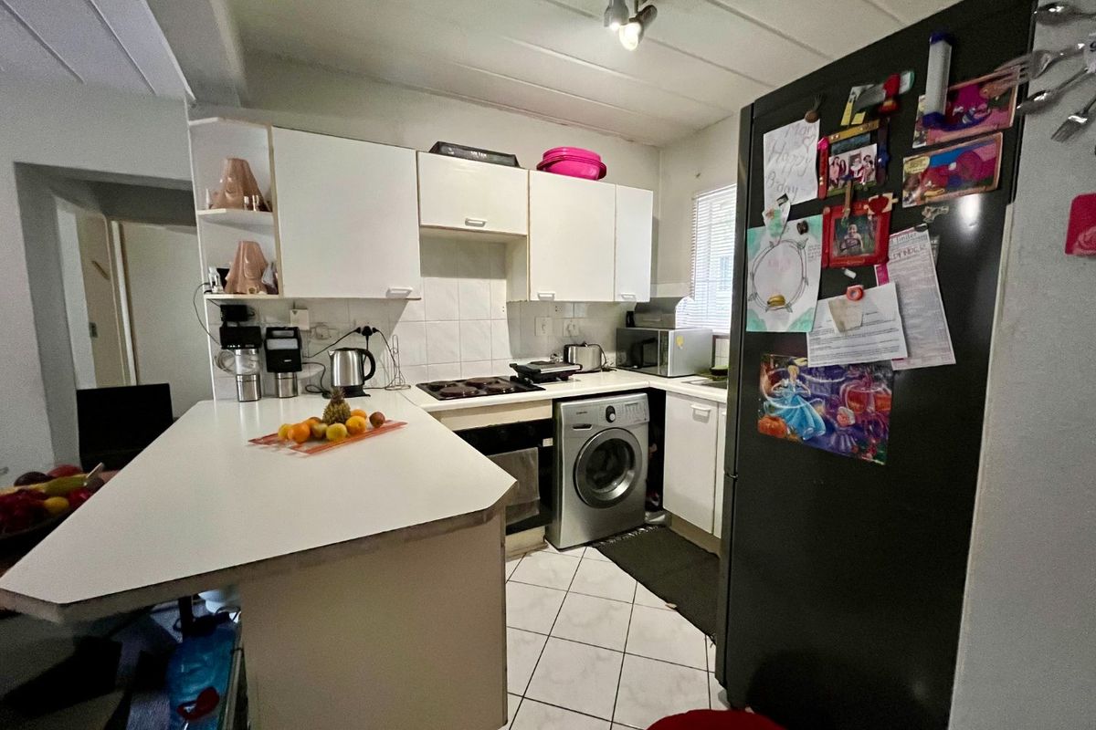 Compact kitchen featuring white built-in cabinetry, a breakfast counter, tiled flooring, and a built-in hob and oven.