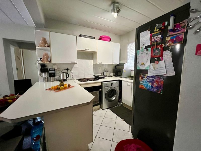 Compact kitchen featuring white built-in cabinetry, a breakfast counter, tiled flooring, and a built-in hob and oven.