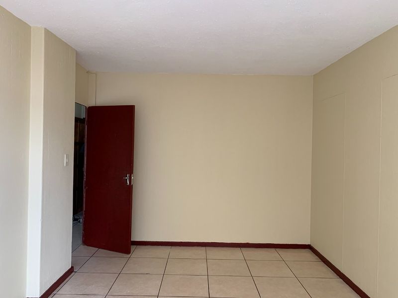An empty bedroom featuring neutral wall paint, tiled flooring, and a contrasting red internal door.