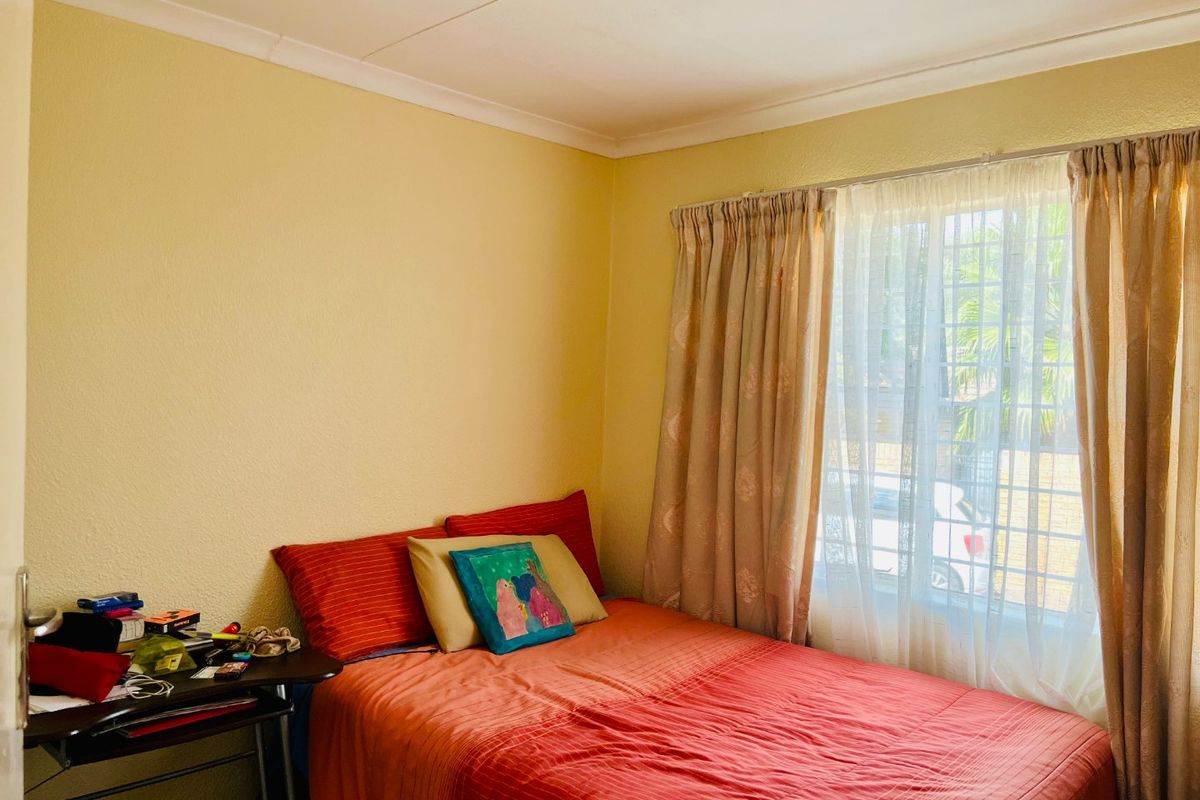 A standard bedroom featuring a window with security bars and coving detail.