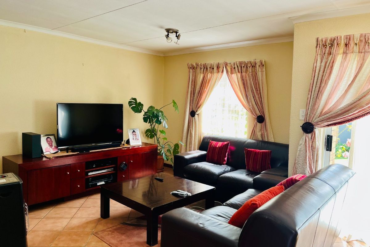 A comfortable living room featuring tiled flooring and a sliding glass door providing natural light and access to the outdoor area.