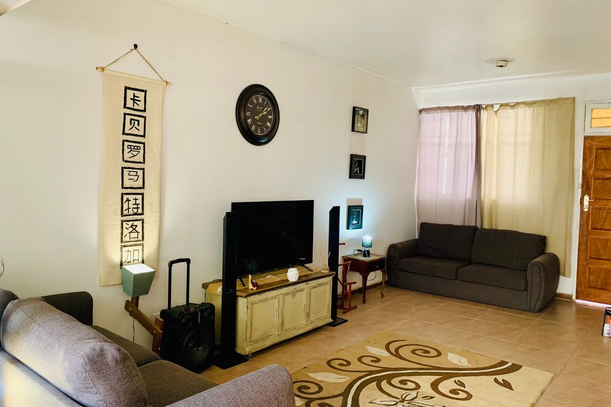 A living room featuring tiled flooring and a timber entrance door, providing a functional and neutral space for relaxation.