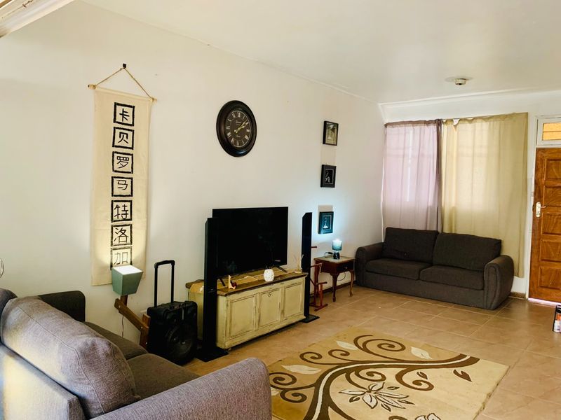A living room featuring tiled flooring and a timber entrance door, providing a functional and neutral space for relaxation.