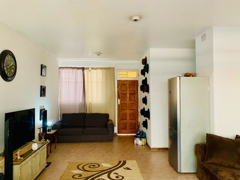 Open plan living area featuring tiled flooring and a solid timber entrance door, providing a functional and accessible layout for the apartment.
