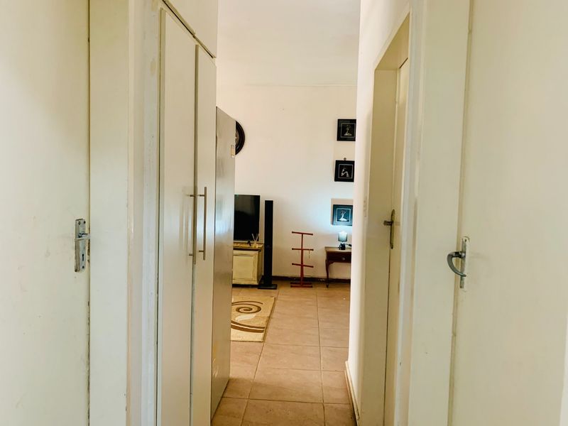 A functional hallway featuring built-in storage cupboards and tiled flooring, providing access to the main living area of the apartment.