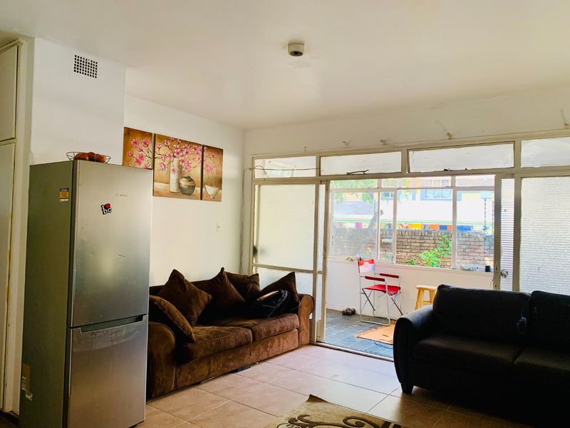 Living area featuring tiled flooring and large sliding glass doors leading to an outdoor patio space, providing natural light and access to the exterior.