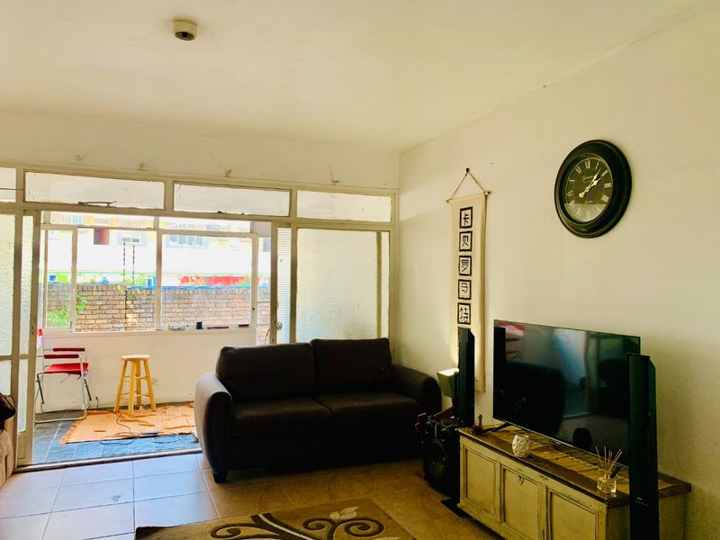 A living room featuring tiled flooring and large sliding glass doors leading to an enclosed balcony area.