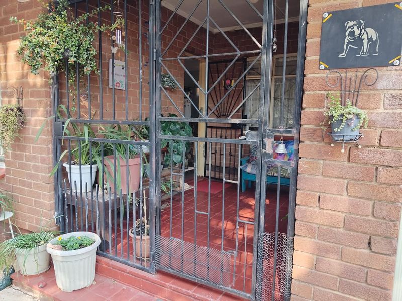 A secure entrance area featuring a metal security gate, brick exterior walls, and tiled flooring.
