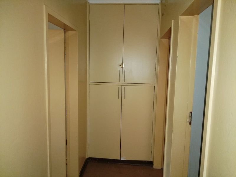 A functional hallway featuring a tall, built-in storage cupboard for linen or household items, providing practical storage space within the home.
