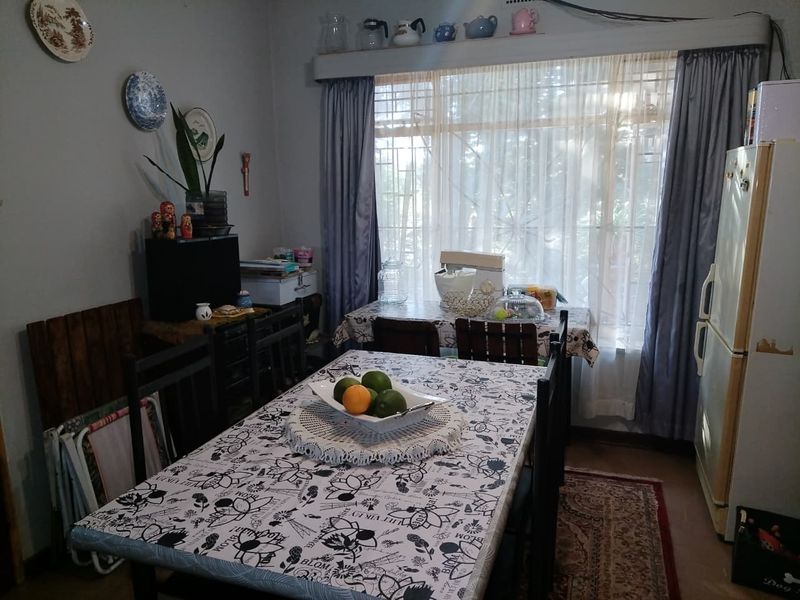 A functional dining room featuring a large window with security bars and curtain rails, providing natural light to the space.