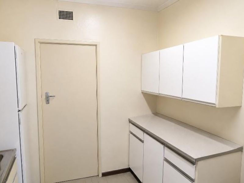 A functional scullery or utility area featuring built-in cabinetry and laminate countertops, providing additional storage and workspace.