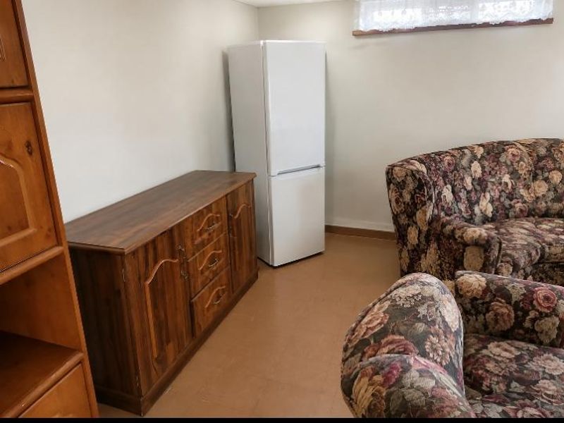 A living area featuring vinyl flooring and a window with a valance, providing a functional space for relaxation.