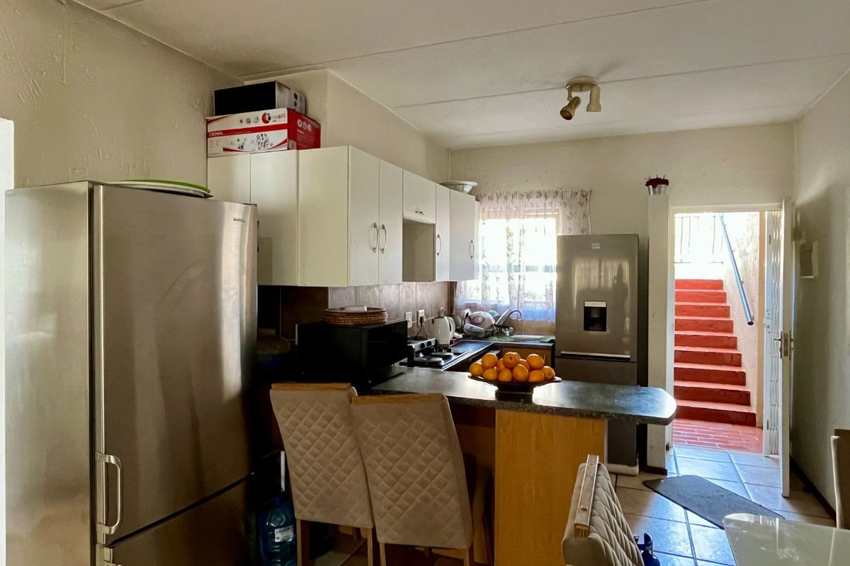 Functional kitchen featuring built-in cabinetry, laminate countertops, and a breakfast bar, with direct access to an outdoor staircase area.