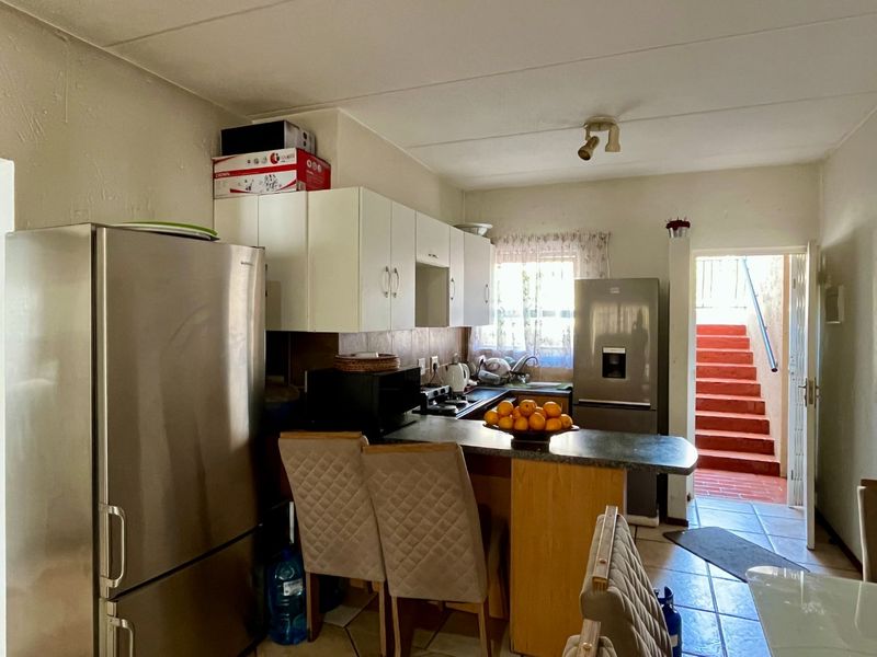 Functional kitchen featuring built-in cabinetry, laminate countertops, and a breakfast bar, with direct access to an outdoor staircase area.