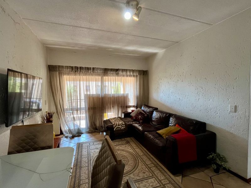 A living room featuring tiled flooring, textured walls, and a sliding glass door providing access to the outdoor area.