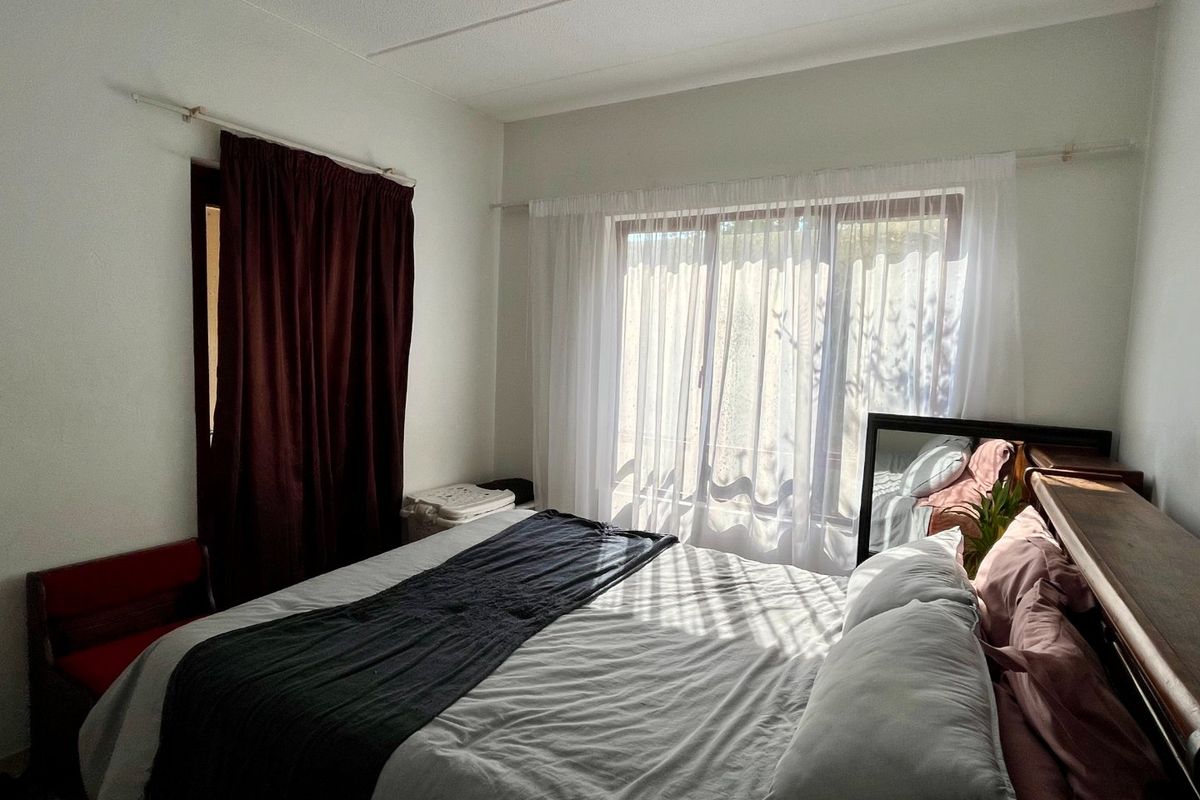 A bedroom featuring a sliding glass door with natural light, neutral walls, and standard window treatments.