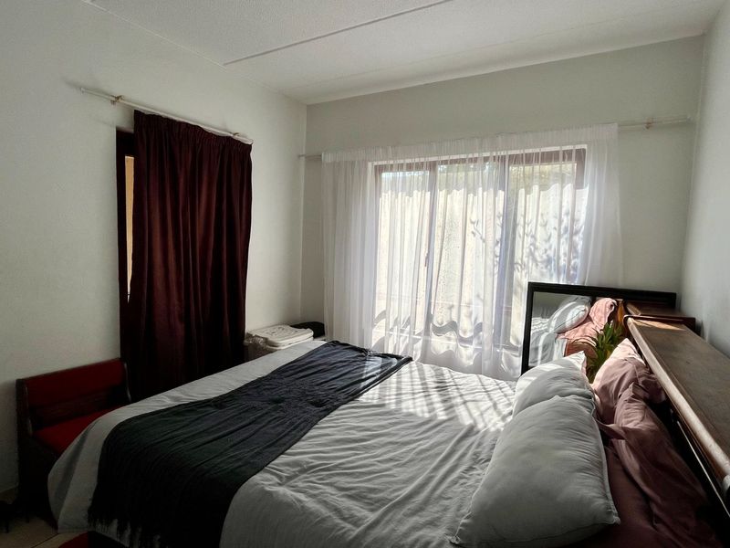 A bedroom featuring a sliding glass door with natural light, neutral walls, and standard window treatments.