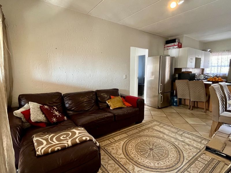 Open-plan living area featuring tiled flooring and a functional kitchen with built-in cabinetry and a breakfast island.