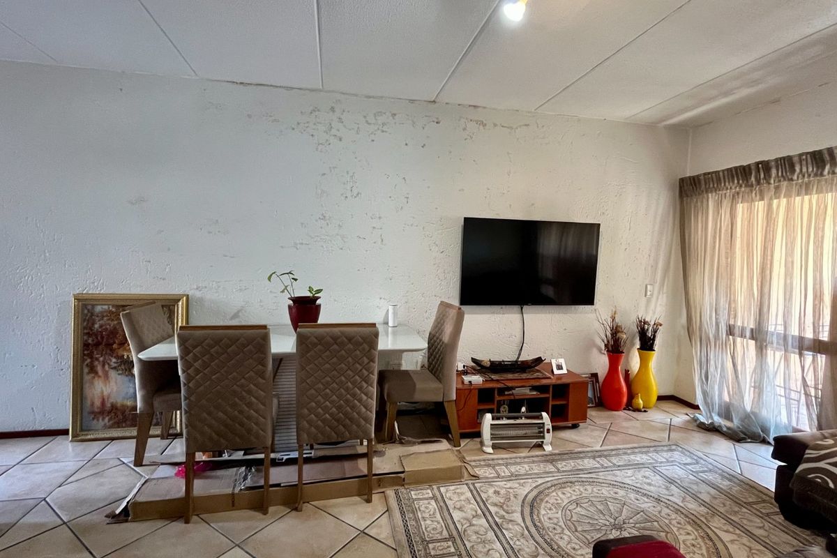 Living room area featuring tiled flooring and a sliding glass door, currently showing significant wear to the wall finishes.