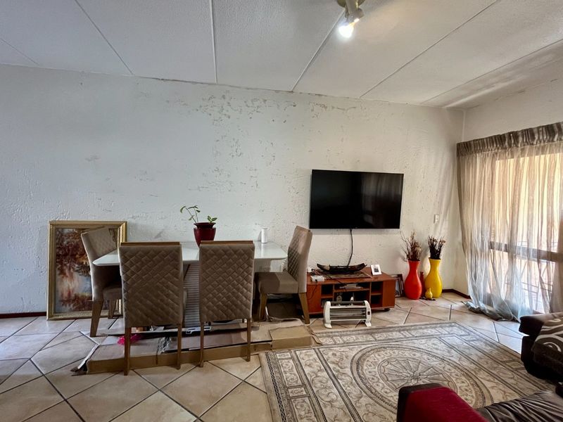 Living room area featuring tiled flooring and a sliding glass door, currently showing significant wear to the wall finishes.