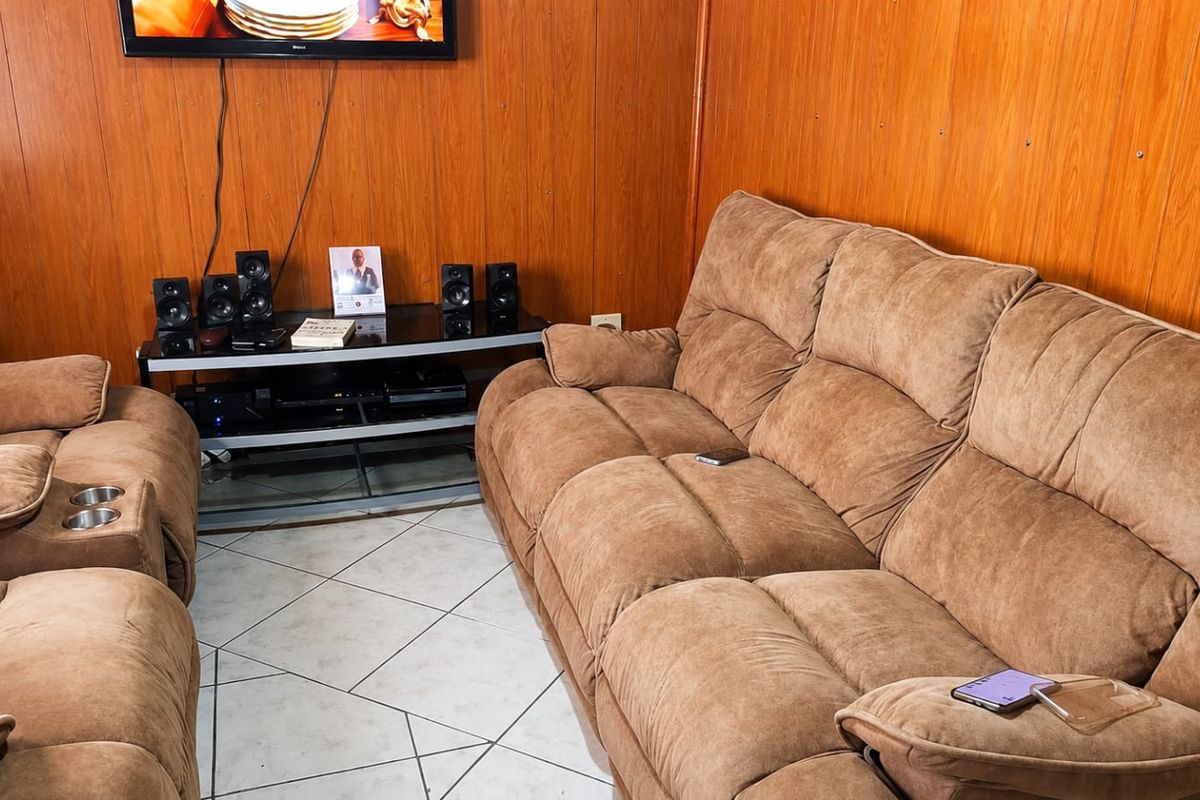A living room featuring wood-paneled walls and ceramic tile flooring, providing a functional space for relaxation.