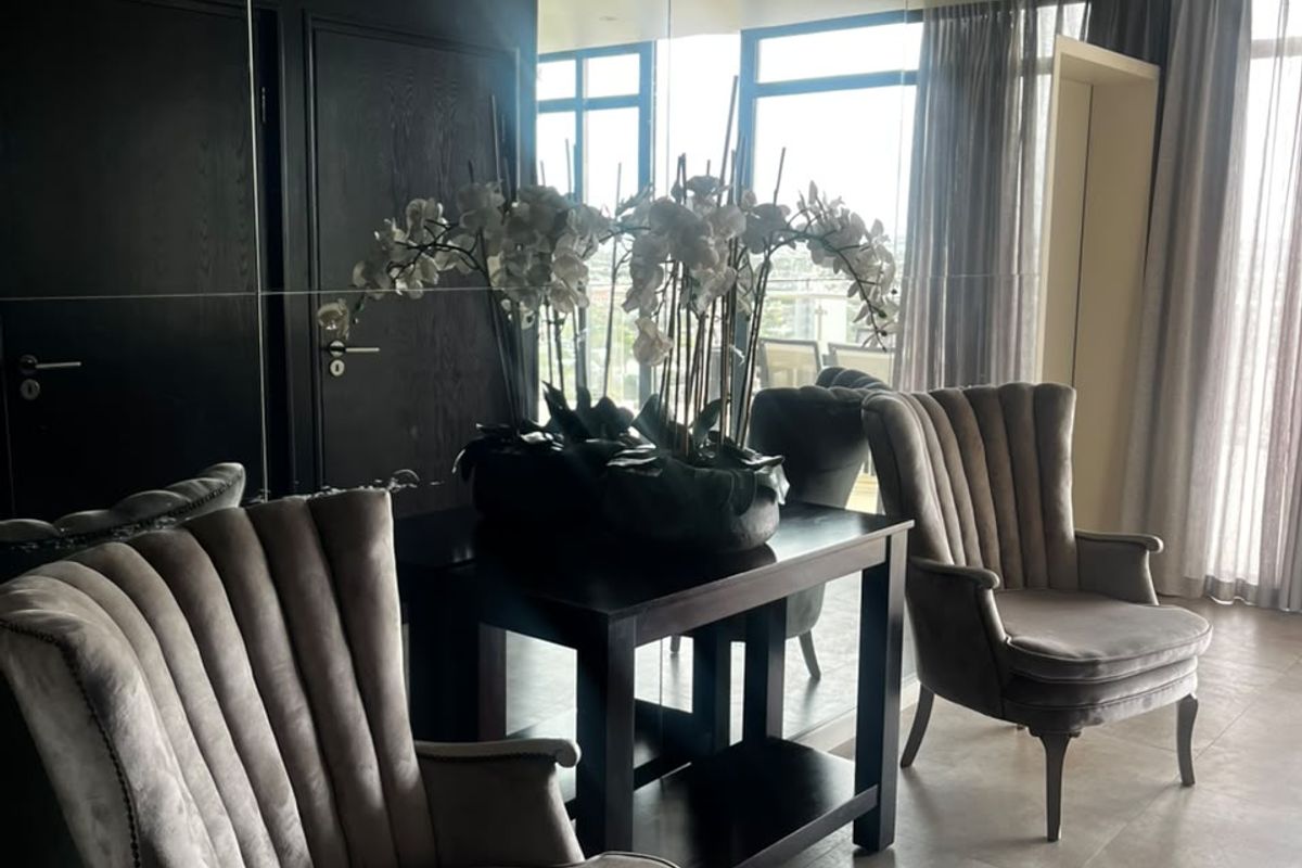 A modern living area featuring large mirrored wall panels, recessed ceiling lighting, and neutral tiled flooring, creating a bright and spacious atmosphere.