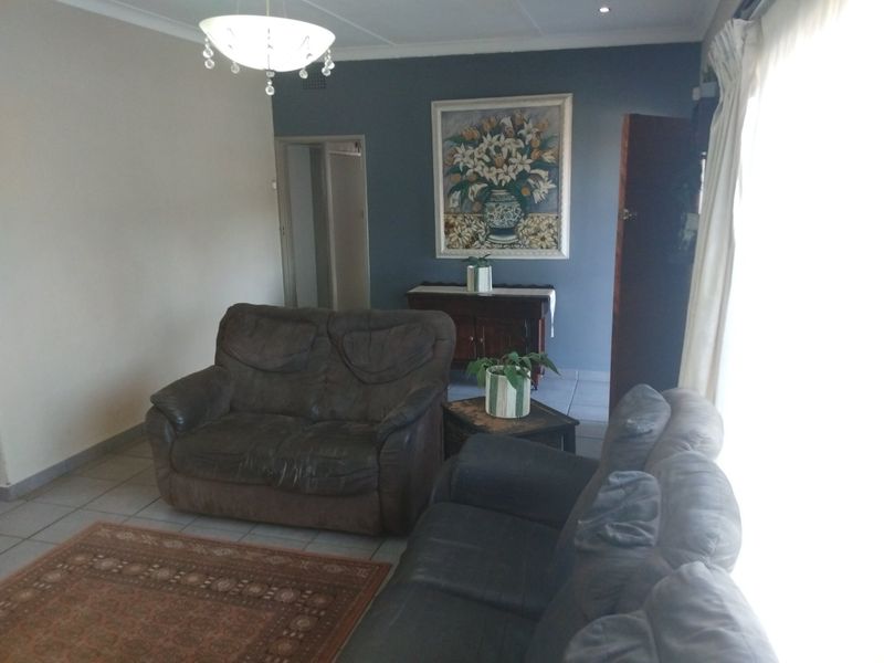 A comfortable living room featuring tiled flooring, a decorative pendant light, and a feature wall, offering a functional space for relaxation.