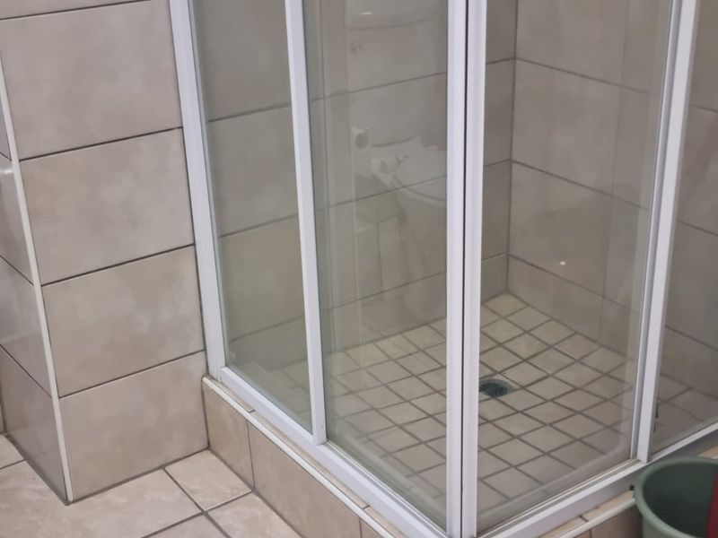A functional bathroom featuring a corner shower enclosure with tiled walls and flooring.