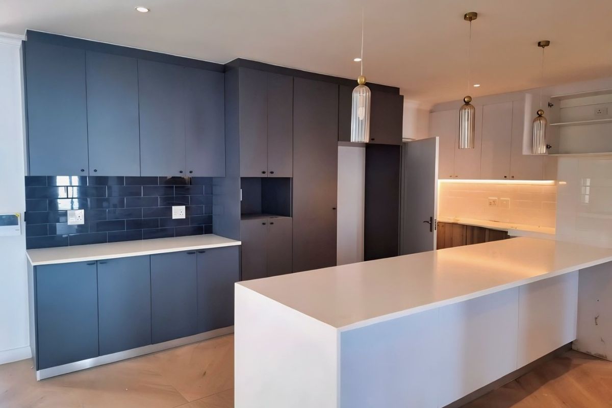 Modern kitchen featuring dark blue and white cabinetry, quartz countertops, a large central island, and stylish pendant lighting.