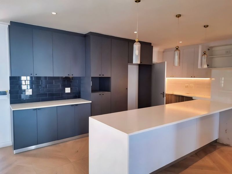 Modern kitchen featuring dark blue and white cabinetry, quartz countertops, a large central island, and stylish pendant lighting.