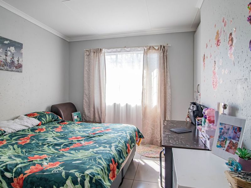 A standard bedroom featuring tiled flooring and a built-in cupboard, offering a functional space with natural light from the window.