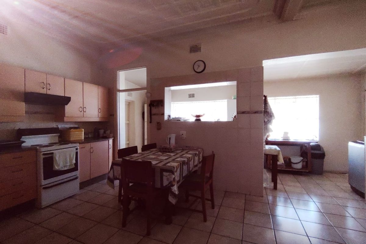 A functional kitchen featuring built-in cabinetry, a freestanding stove with extractor fan, and tiled flooring, with a convenient pass-through window to the adjacent space.
