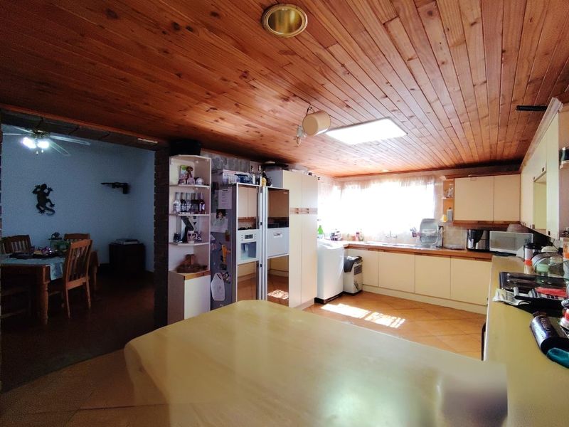 Open-plan kitchen area featuring timber-clad ceilings, tiled flooring, and extensive built-in cabinetry, offering a functional layout with potential for modern updates.
